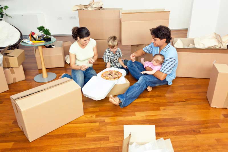 Eltern und zwei Kinder essen Pizza zwischen Umzugskartons